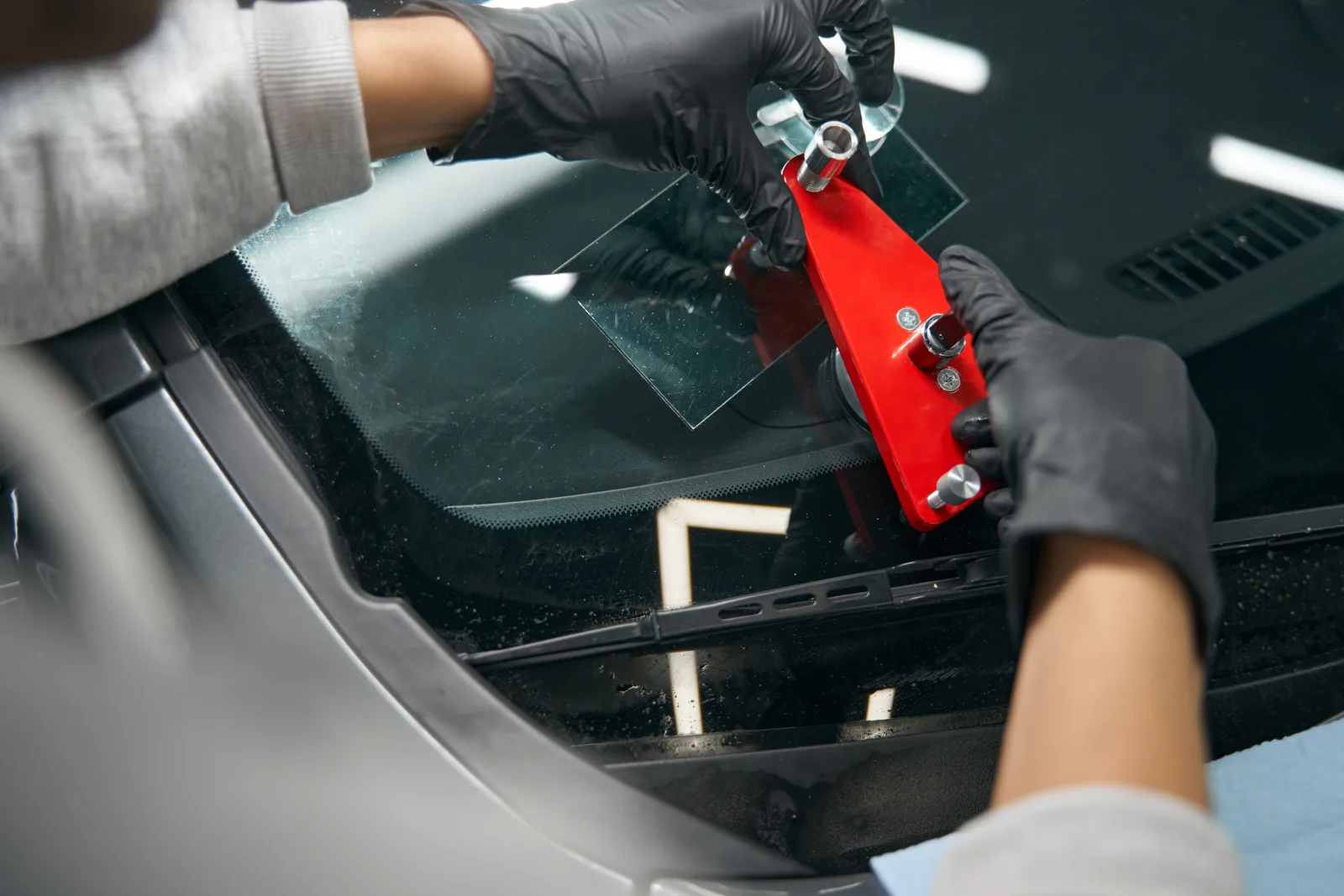 Technician using a red bridge tool to repair a windshield